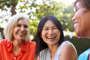3 women laughing, one is asian, other is blond and the other is black