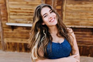 beautiful smiling woman with wavy hair and arms crossed