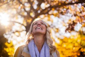 smiling middle aged woman looking up near trees