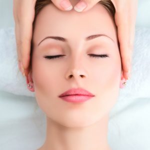 beautiful woman's face with eyes closed and hands on her head